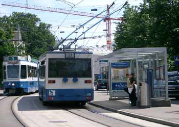 Trolleybus and tram call at road centre stop with island platforms in Zürich, Switzerland.