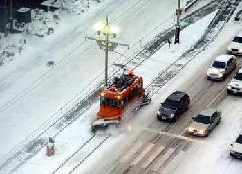 A snowbroom tram clears the track of snow.