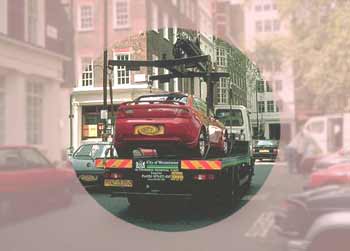 A car on an illegal-parking tow-away flatbed lorry. Seen as if looking through a rose-tinted lens with a clear central area.