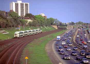 Commuter train alongside a busy urban motorway.
