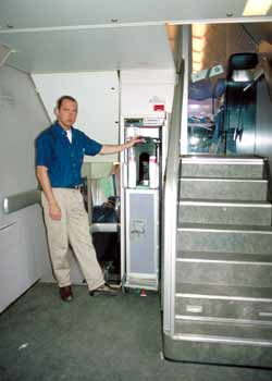 An 'at seat' refreshment trolley attendant is about to load his trolley into a double-deck train's dumb-waiter.