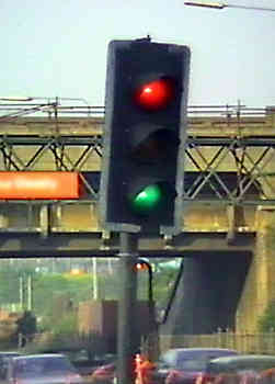 Malfunctioning traffic signals showing red and green at the same time - also leaning at unsafe angle as if about to fall over.